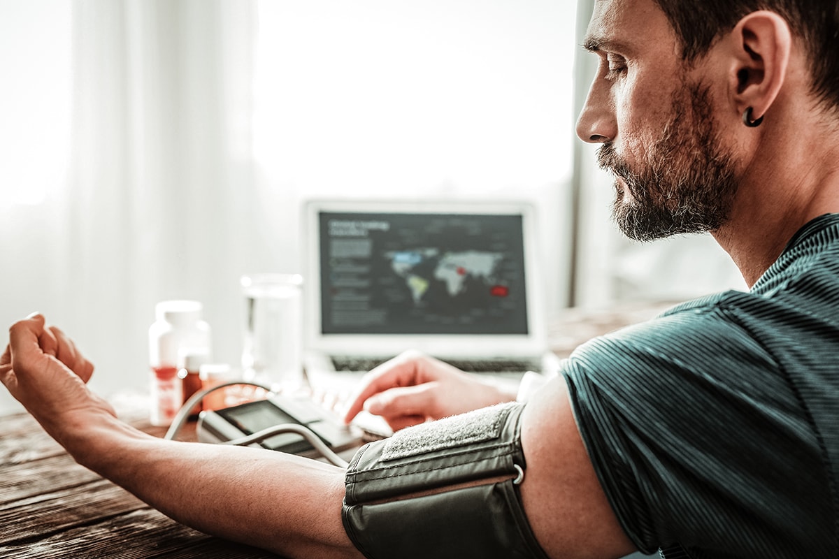 Man looking at his hand while measuring his blood pressure
